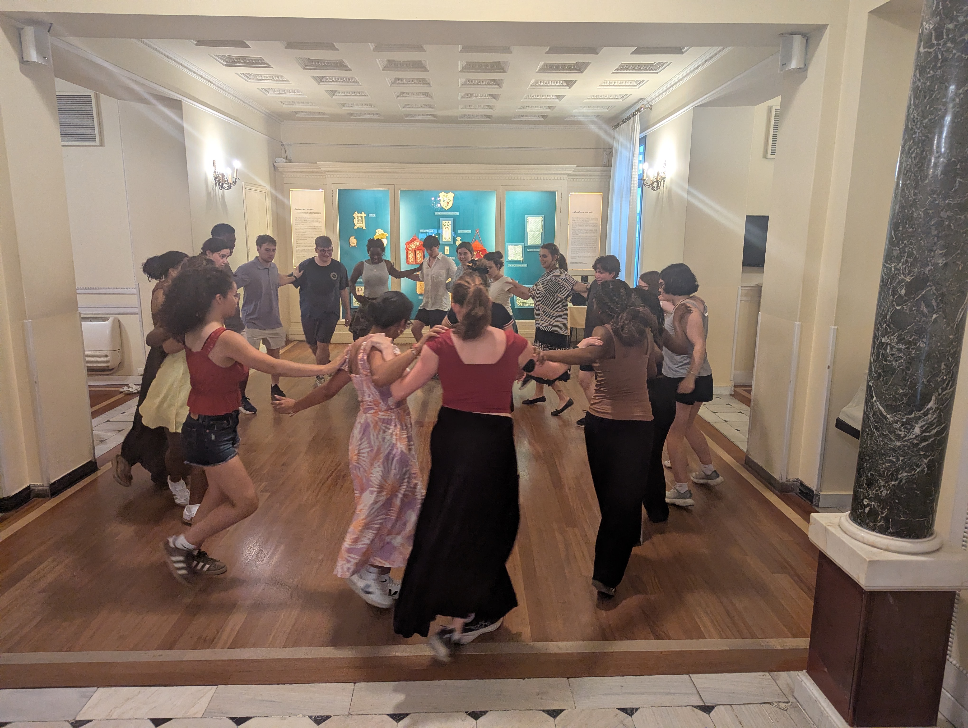 Students attending the Greek dance lesson dancing in a circle.